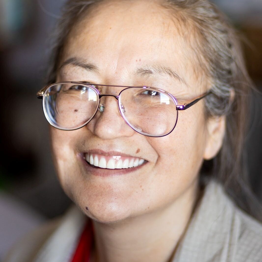 A woman with glasses smiling for the camera.